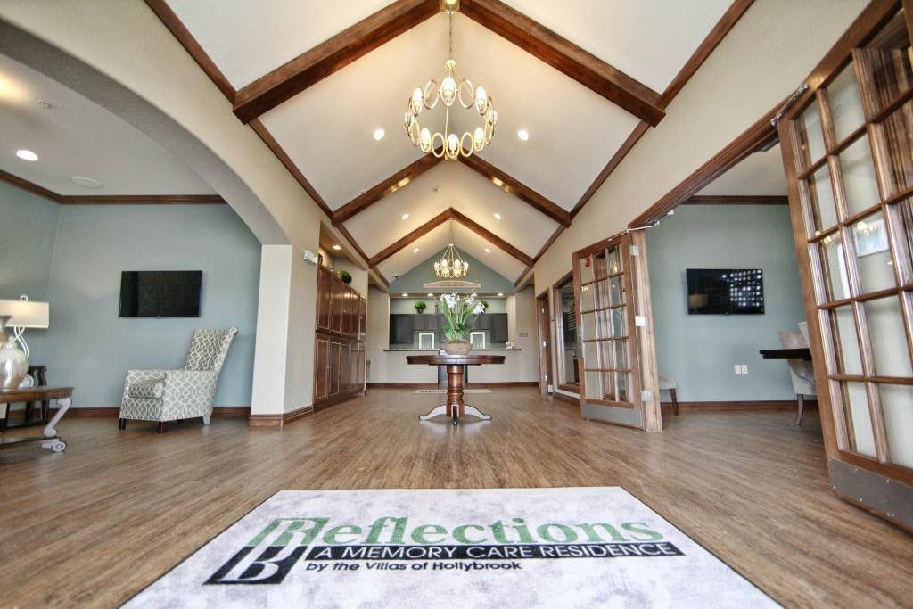 A spacious interior with vaulted ceilings, featuring wooden beams and an elegant chandelier.