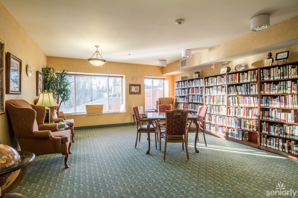 A cozy library reading room with shelves full of books and a table surrounded by chairs.