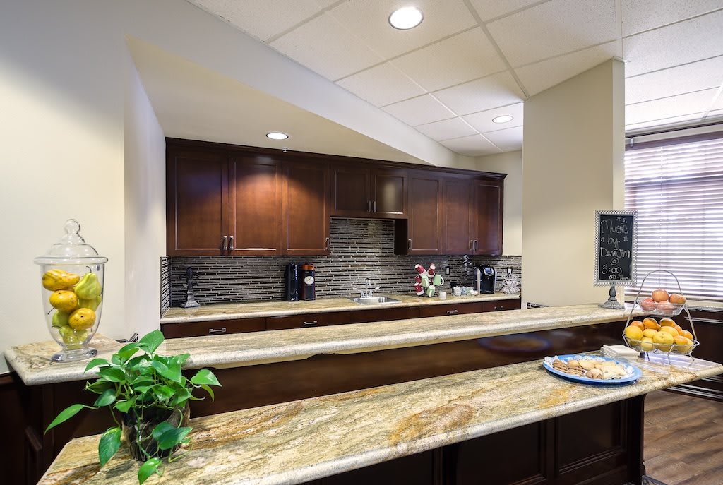 A modern kitchen interior with dark wood cabinets and a marble countertop.