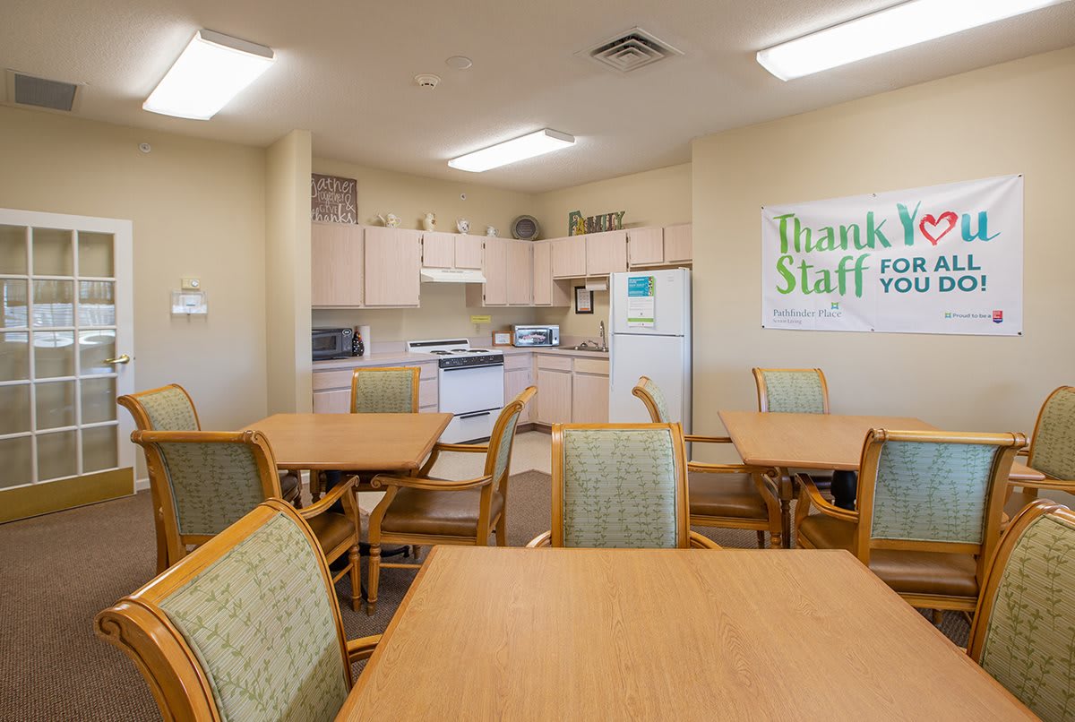 An office break room with tables, chairs, and kitchen appliances.