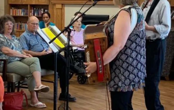 A performer plays the accordion for an attentive audience in an indoor setting.