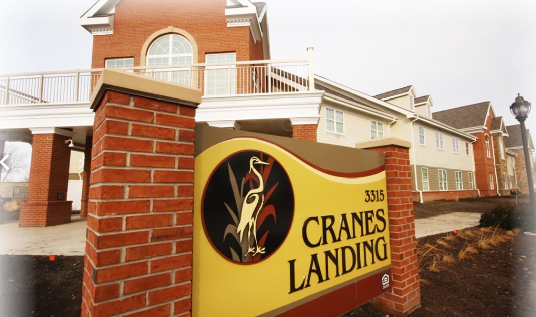 A sign for Cranes Landing in front of a building.