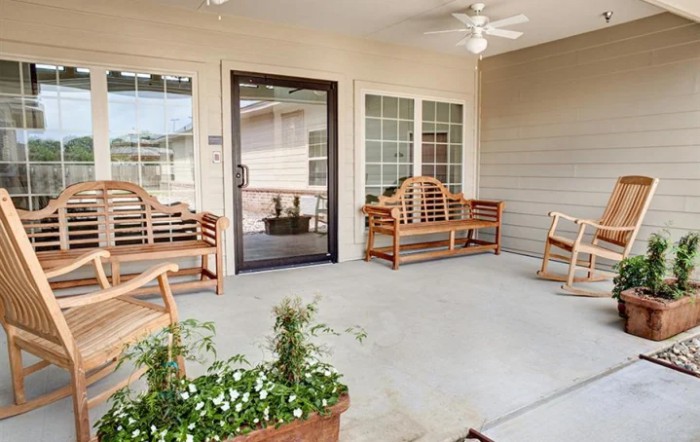 A cozy porch with wooden furniture and ceiling fan.
