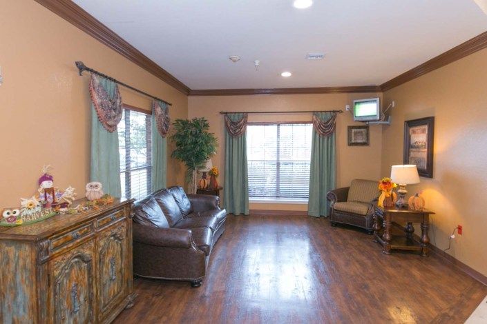 A cozy living room with a sofa, armchair, and wooden flooring.
