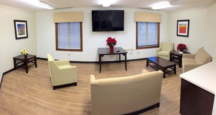 A cozy living room with modern furnishings, featuring a TV, sofas, coffee tables, and decor elements like poinsettia flowers.