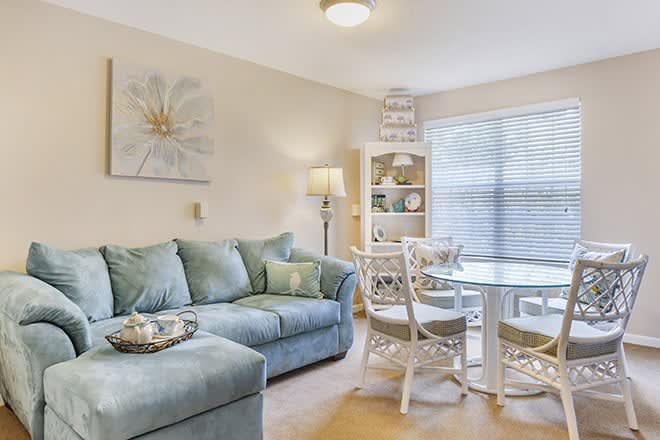 A cozy living room with a blue sofa and dining area, accentuated by natural light and elegant decor.