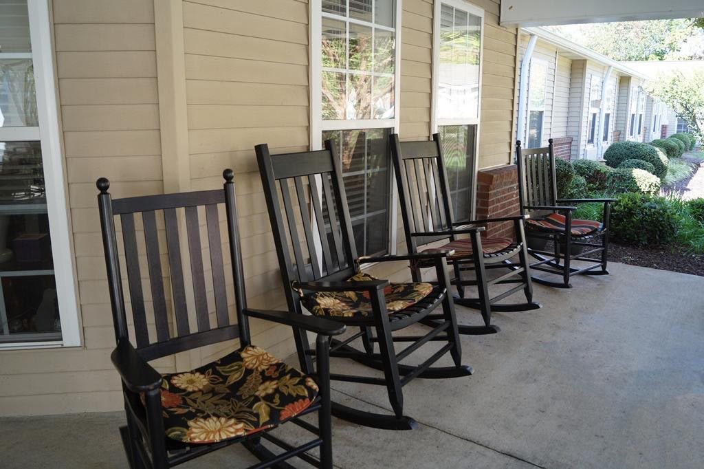 A row of rocking chairs on a porch, providing a cozy outdoor seating area.