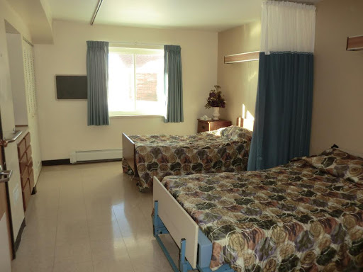 A cozy hotel room featuring two beds with floral bedding and a view out the window.