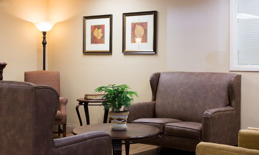 A cozy living room with comfortable chairs and framed artwork on the wall.