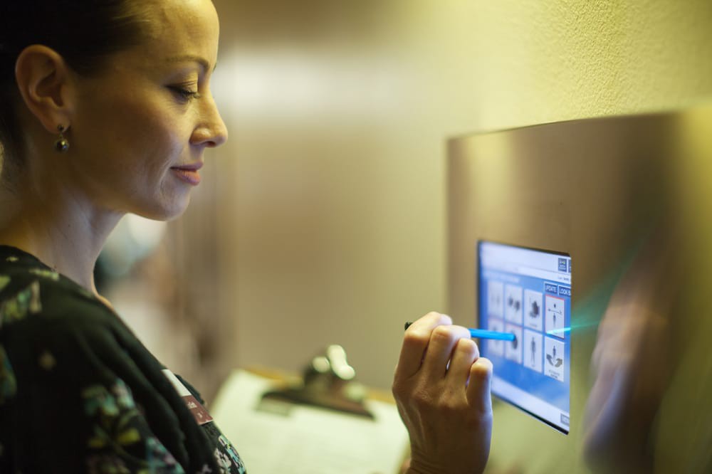 A healthcare professional using a touchscreen in a medical setting.