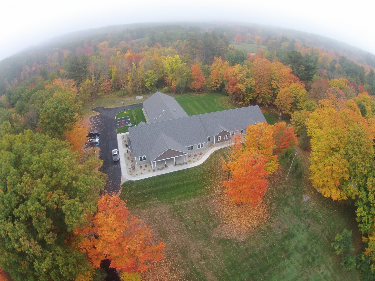 An aerial view of a building surrounded by vibrant autumn foliage.