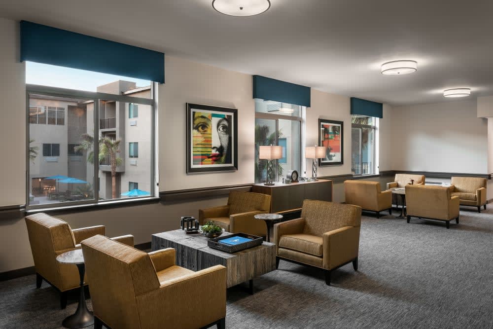 A modern waiting area featuring comfortable armchairs, large windows with natural light, and decorative artwork on the walls.