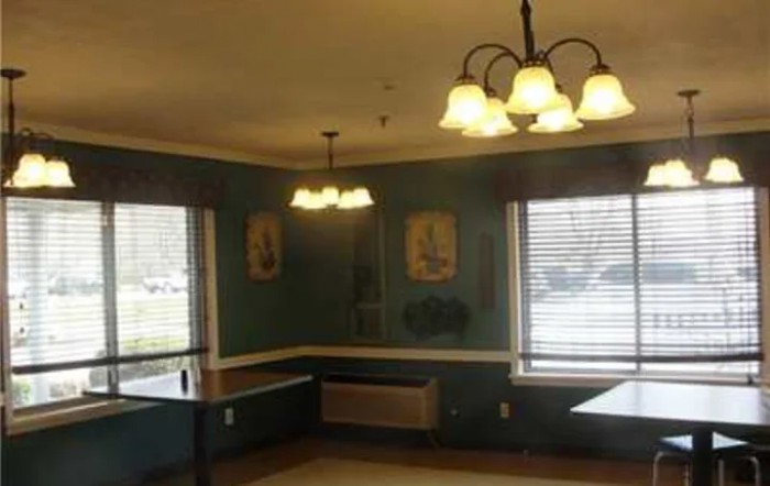 A cozy dining room with large windows, wall art, and a chandelier.