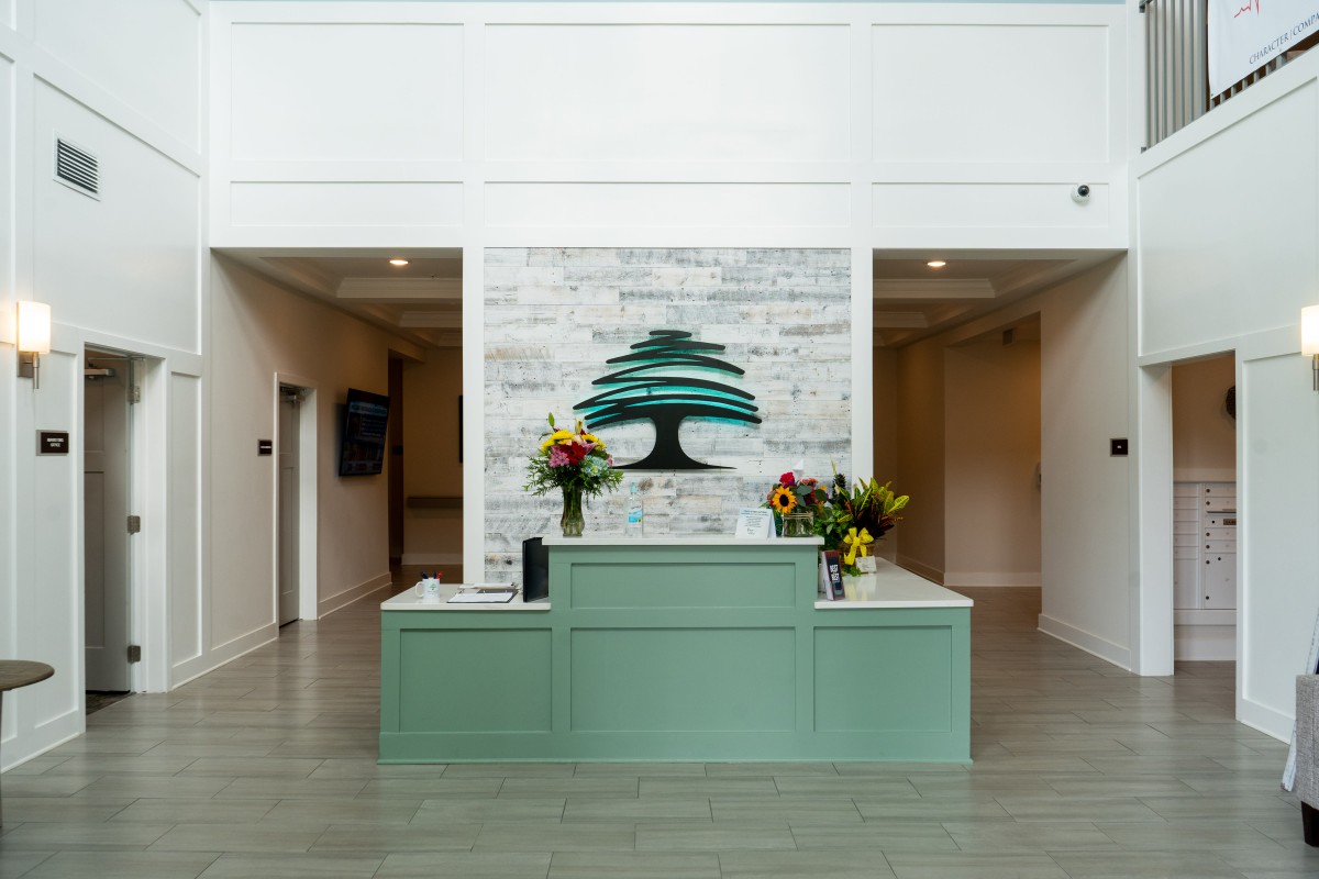 A modern reception area featuring a decorative artwork of a tree and floral arrangements.