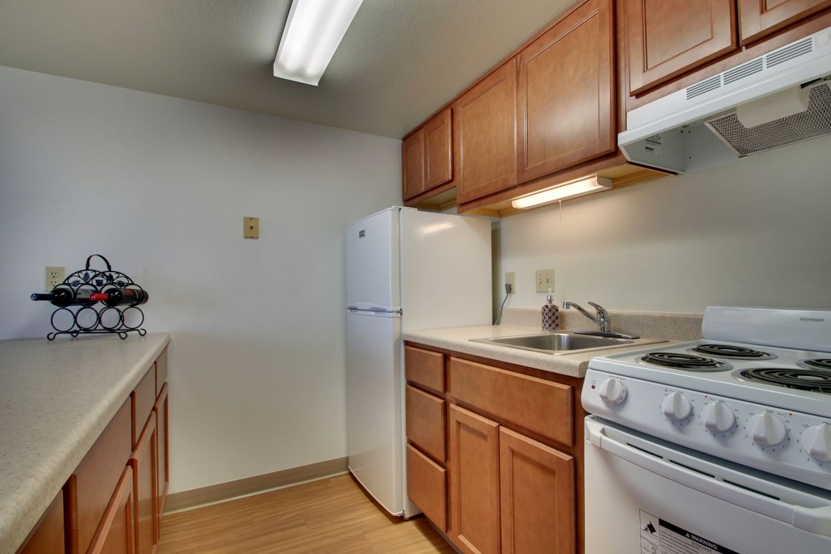 A compact kitchen with wooden cabinets, a white stove, and a refrigerator.