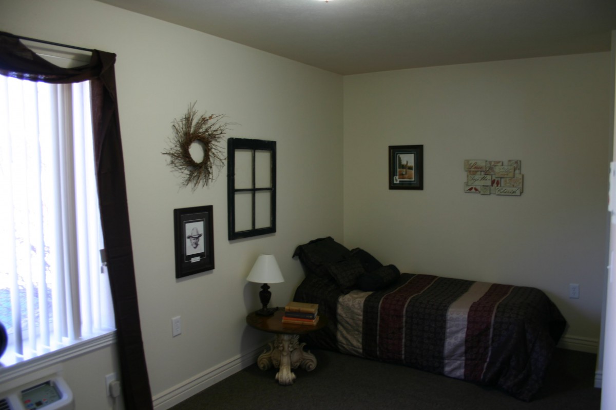 A minimalist bedroom with a single bed, wall art, and a bedside lamp.