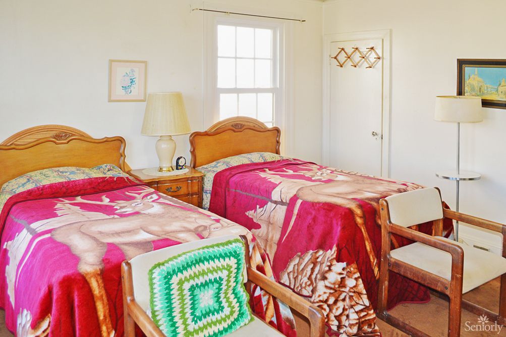 A cozy bedroom with two twin beds featuring colorful blankets and wooden furniture.