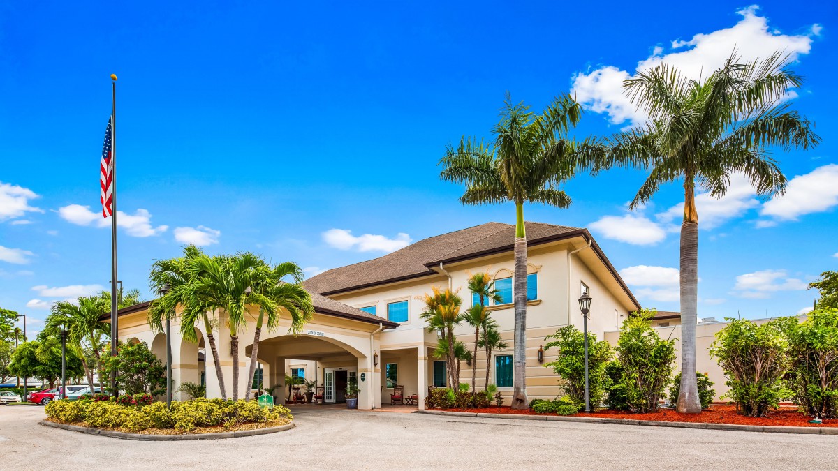 A tropical-style residential building with palm trees and a welcoming entrance.