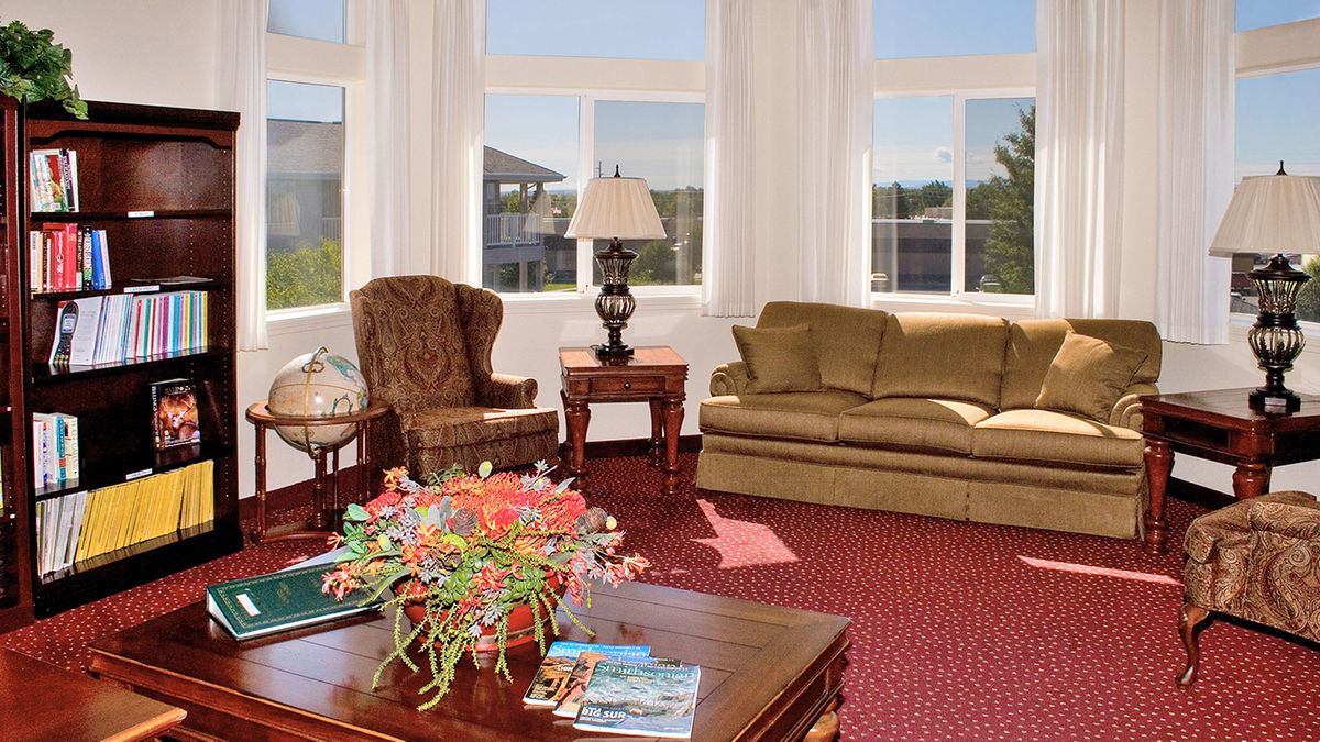A cozy living room with a sofa, armchair, and coffee table adorned with flowers.