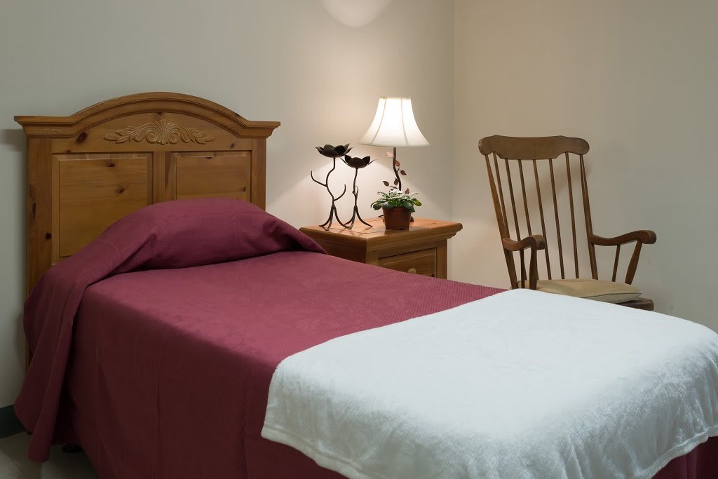 A cozy bedroom with a single bed, nightstand, and rocking chair.