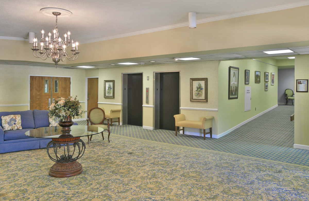 A well-decorated lobby area with elevators, a chandelier, and elegant furnishings.