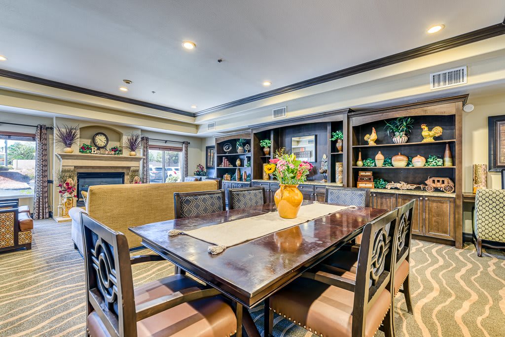 A beautifully designed dining room featuring a large table with ornate chairs, surrounded by bookshelves and elegant decor.