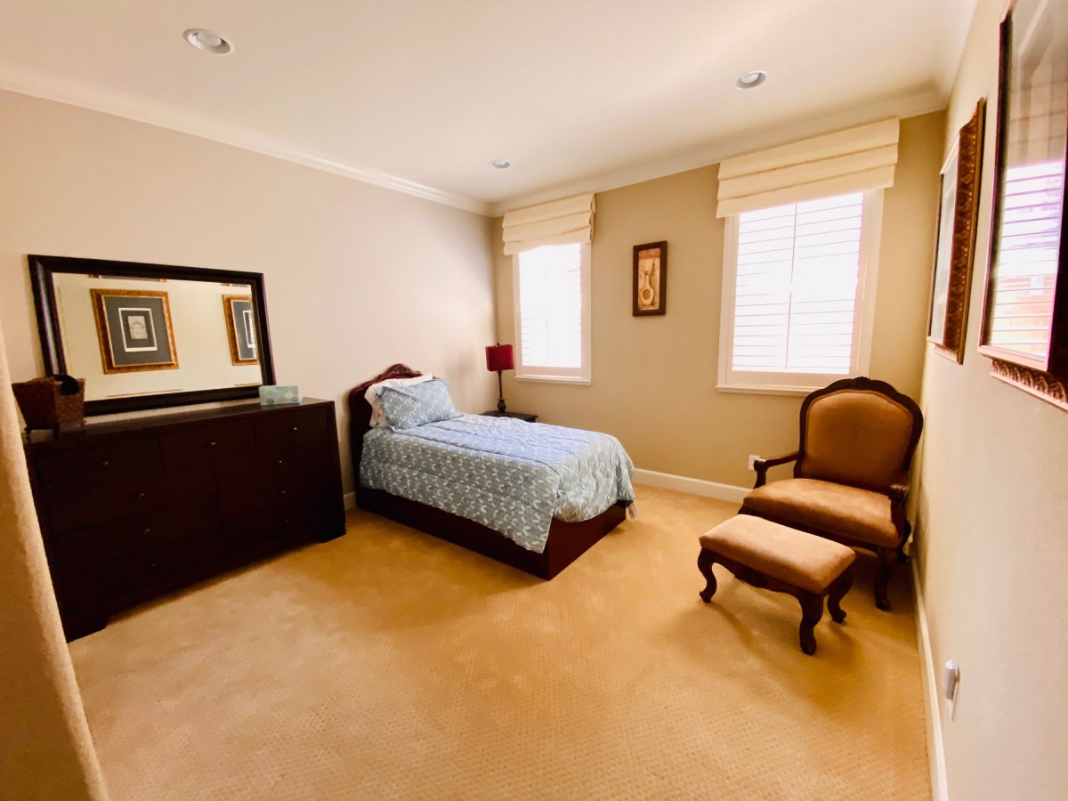 A cozy bedroom with a single bed, dresser, and elegant chair.
