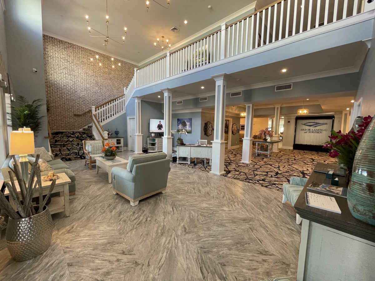 A spacious and modern lobby area with elegant furniture, chandeliers, and grand staircase.