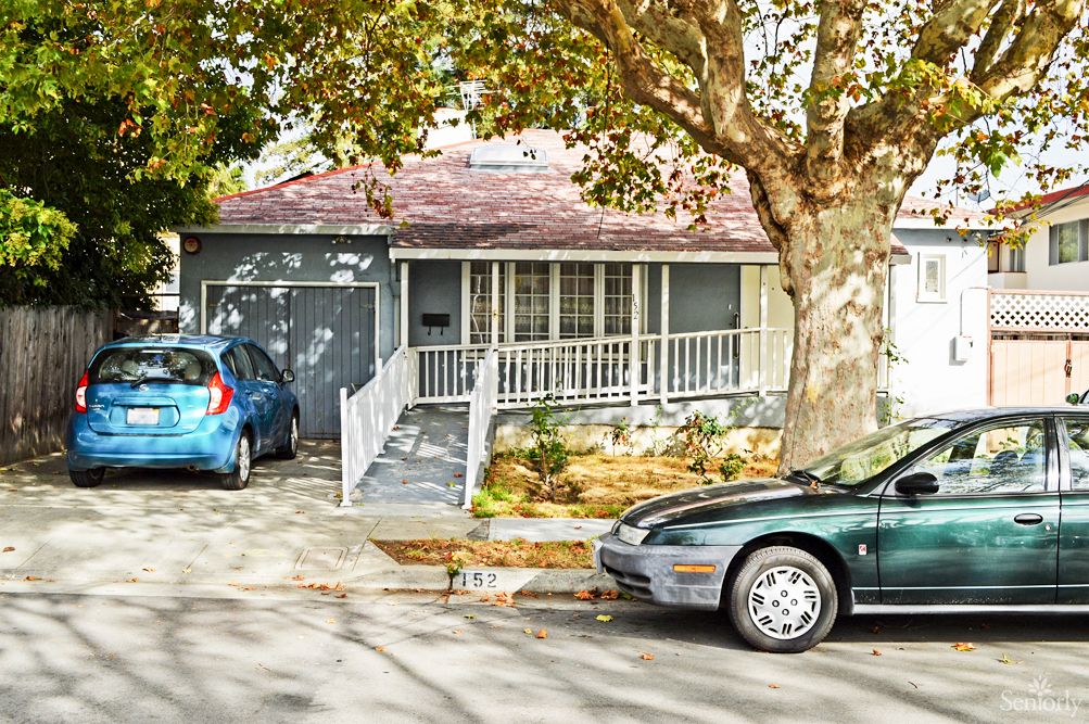 A suburban house with two cars parked in the driveway, surrounded by trees.