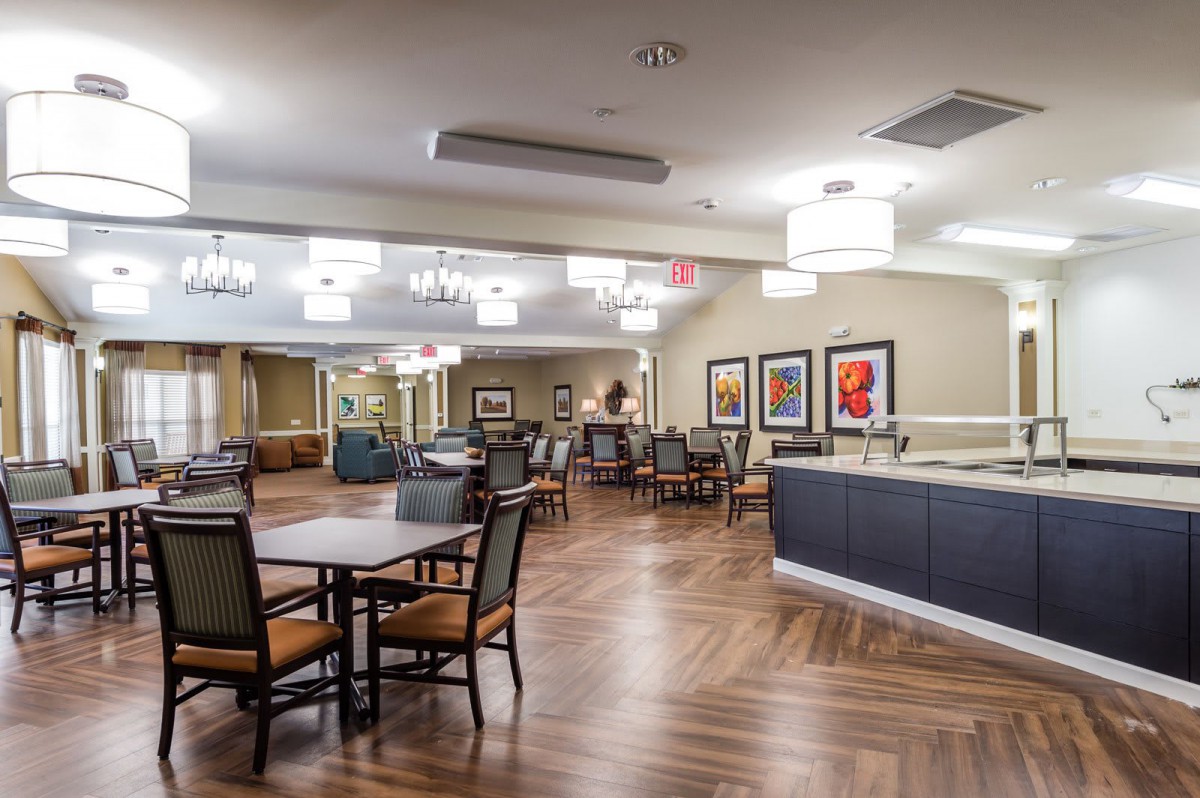 A modern dining area with neatly arranged tables and chairs, adorned with elegant lighting and artwork on the walls.