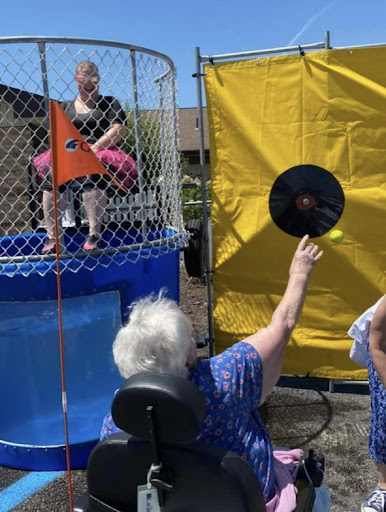 A lively outdoor event featuring a dunk tank, where participants aim to hit the target and splash the person sitting above.