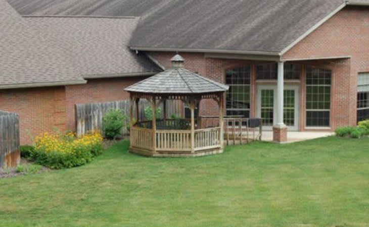 A backyard view featuring a gazebo positioned on a well-maintained lawn next to a house.