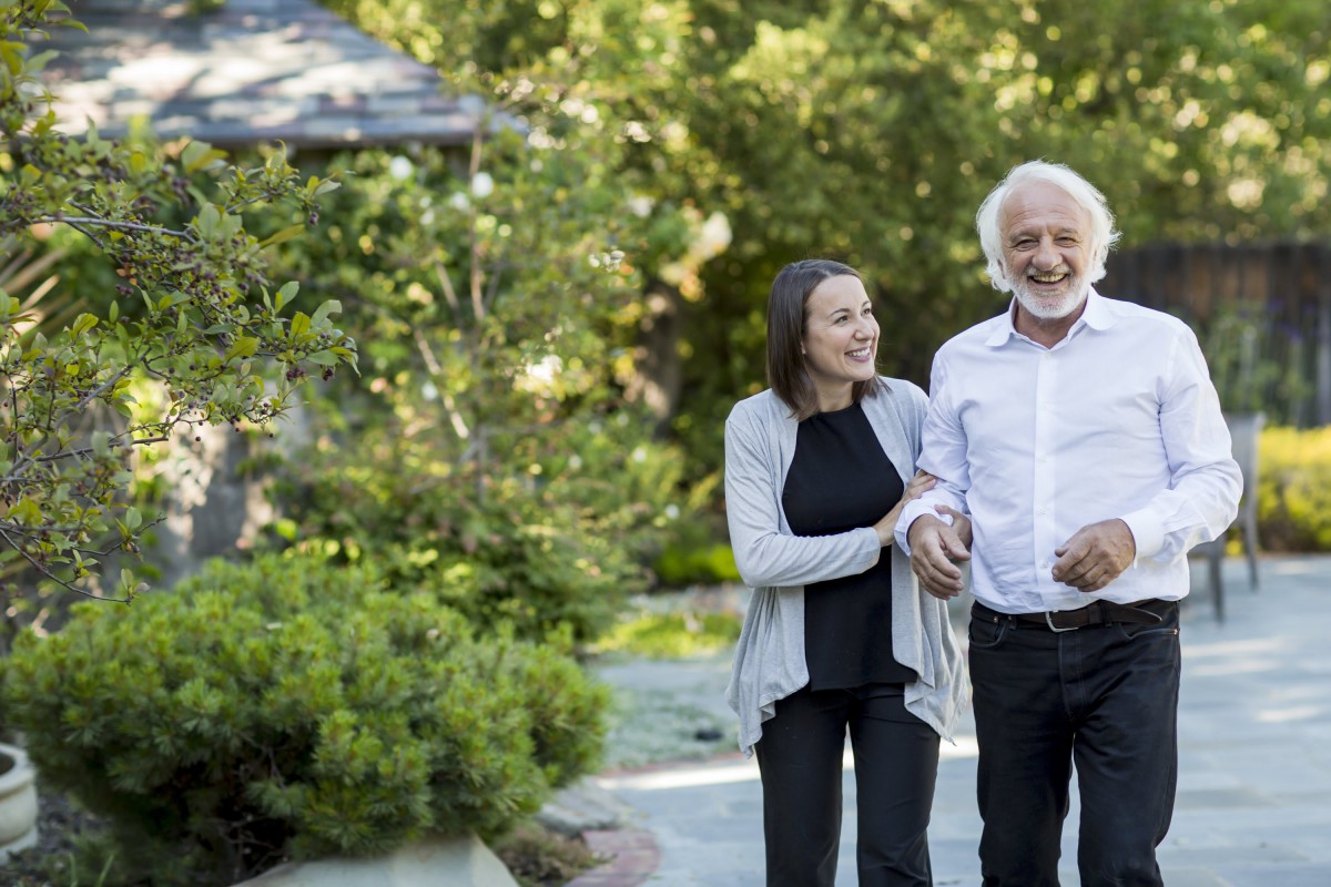 An elderly couple enjoying a walk together in a lush garden.
