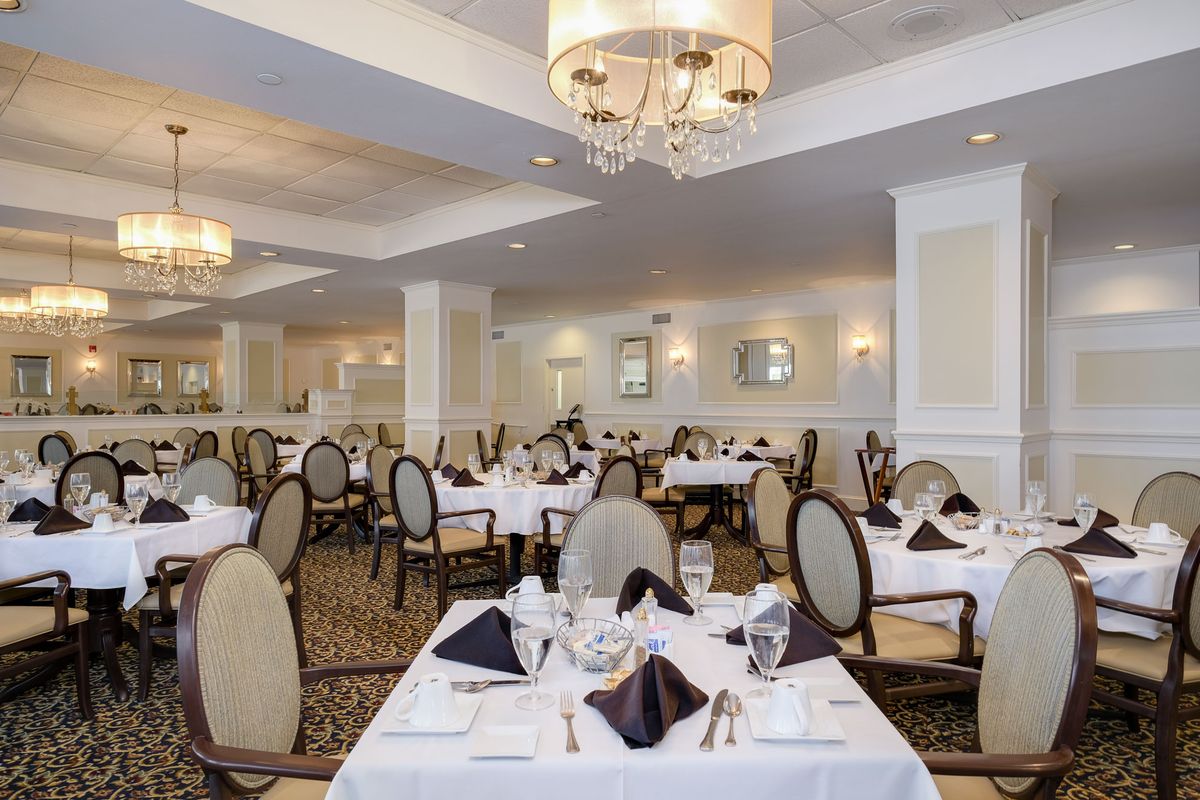 An elegant dining area with neatly arranged tables and chandeliers.