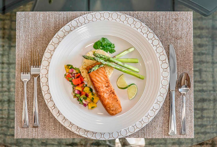 A beautifully presented meal featuring grilled salmon, asparagus, and a colorful vegetable medley.