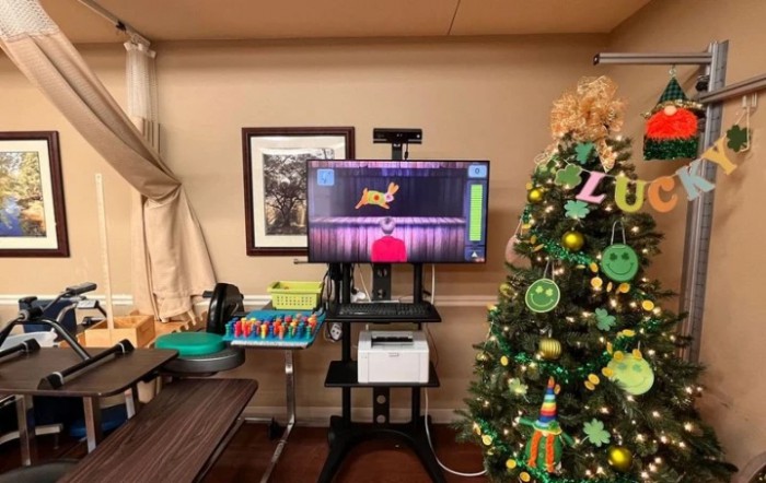 A festive room with a Christmas tree and a video game setup on a monitor.