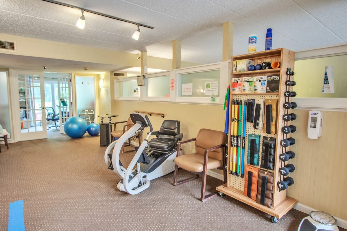 A fitness room equipped with exercise machines, dumbbells, and therapy balls.