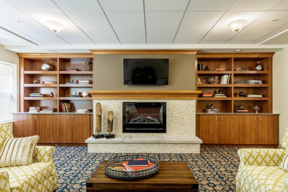 A cozy living room featuring a fireplace with a television above, surrounded by built-in bookshelves.