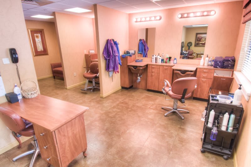 An empty hair salon with styling chairs, mirrors, and salon equipment arranged neatly.