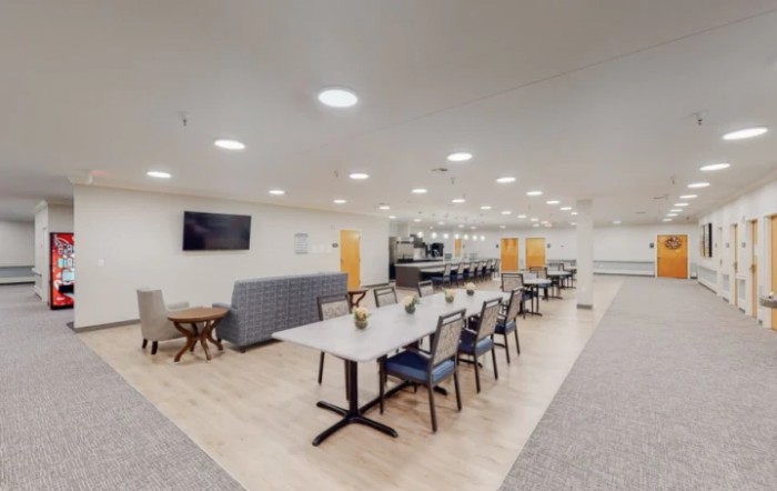 A modern dining area with tables, chairs, and a television mounted on the wall.