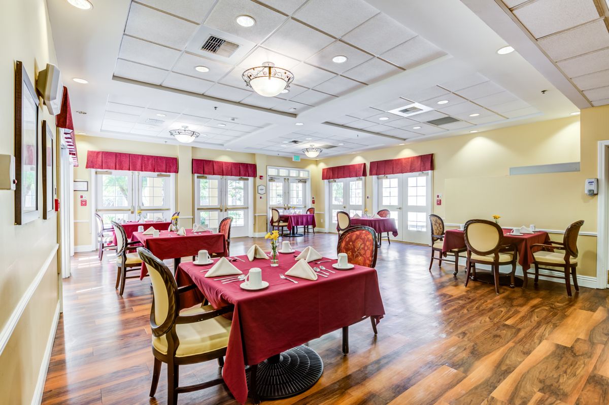 A well-lit dining room with red tablecloths and elegant chairs.