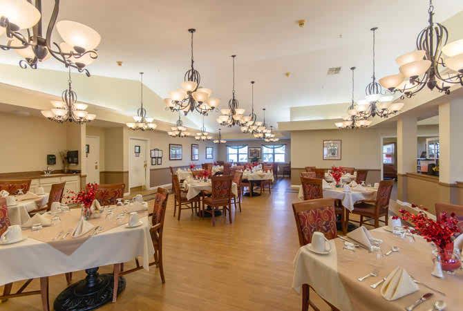 An elegant dining room with neatly arranged tables and chairs, softly lit by chandeliers.