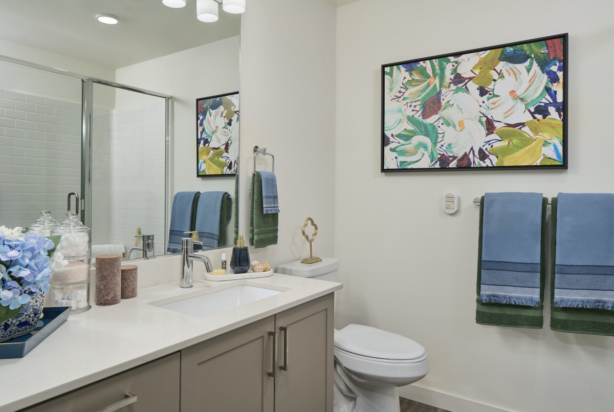 A modern bathroom featuring a sink, toilet, and decorative artwork on the wall.