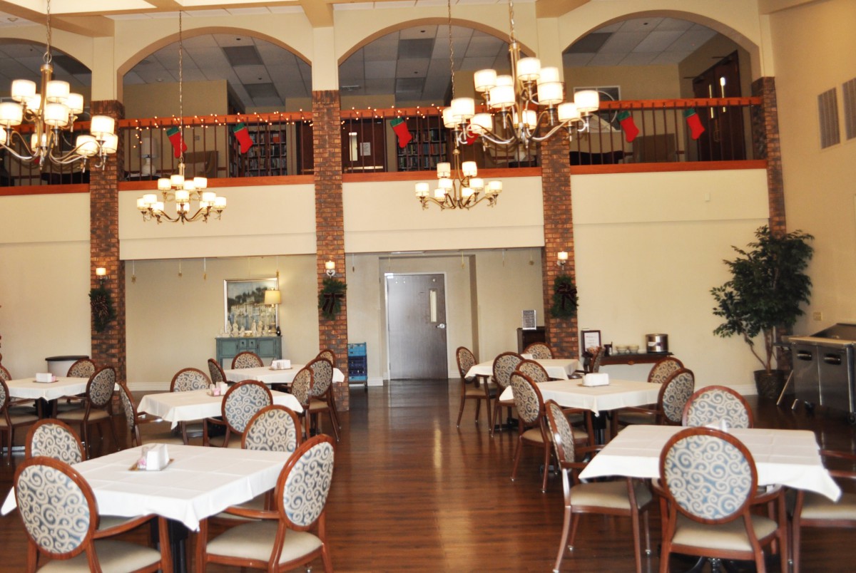 An elegant dining area with neatly arranged tables and chairs, decorated with chandeliers.