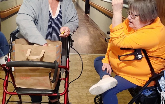 Two people interacting in a hallway, one using a walker.