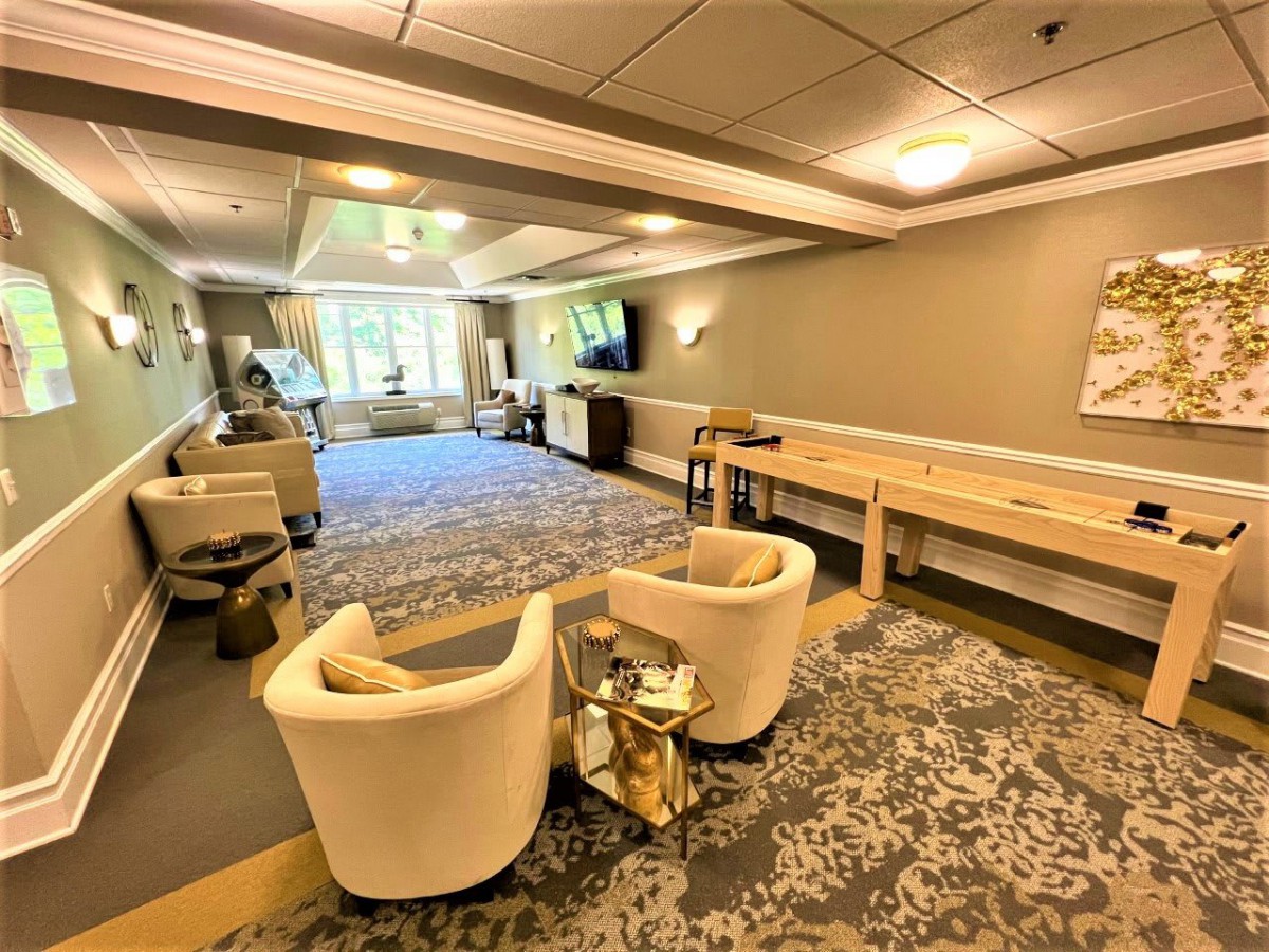A modern lounge space with comfortable seating and a shuffleboard table.
