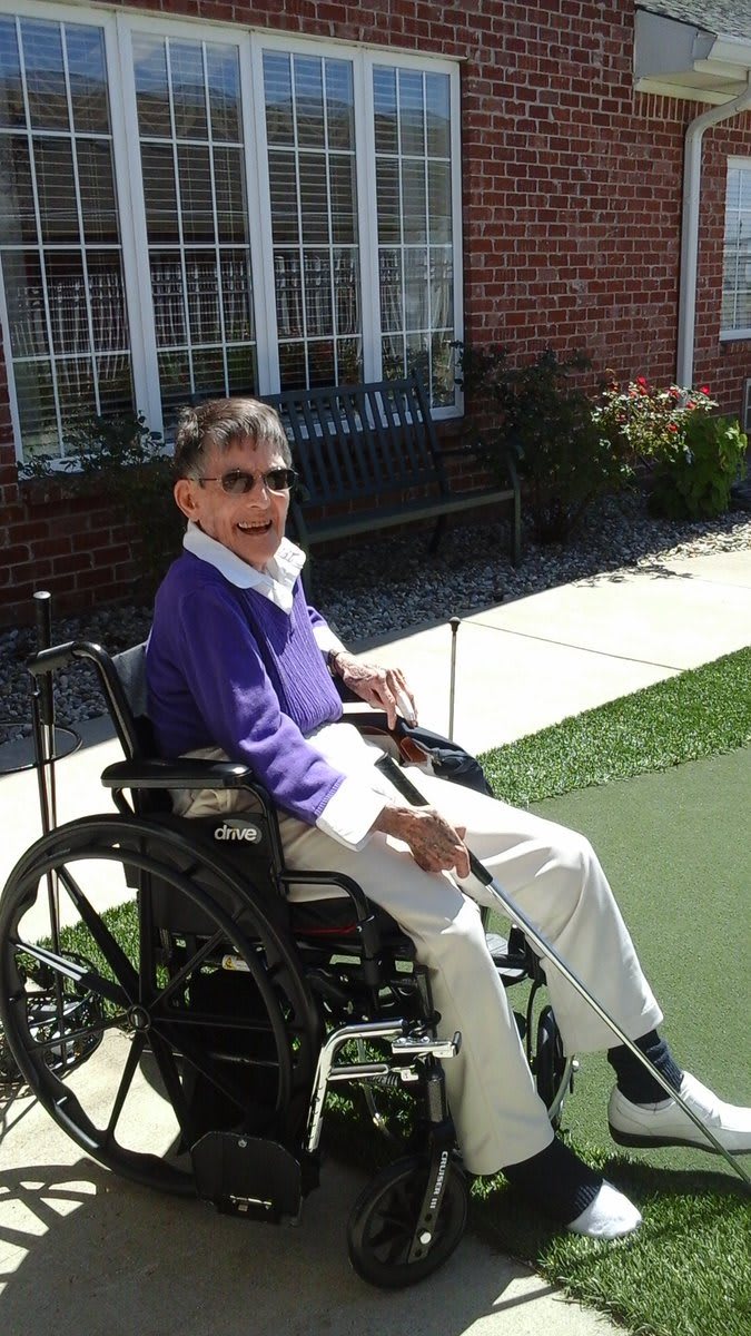 An elderly person in a wheelchair enjoys a sunny day outdoors.