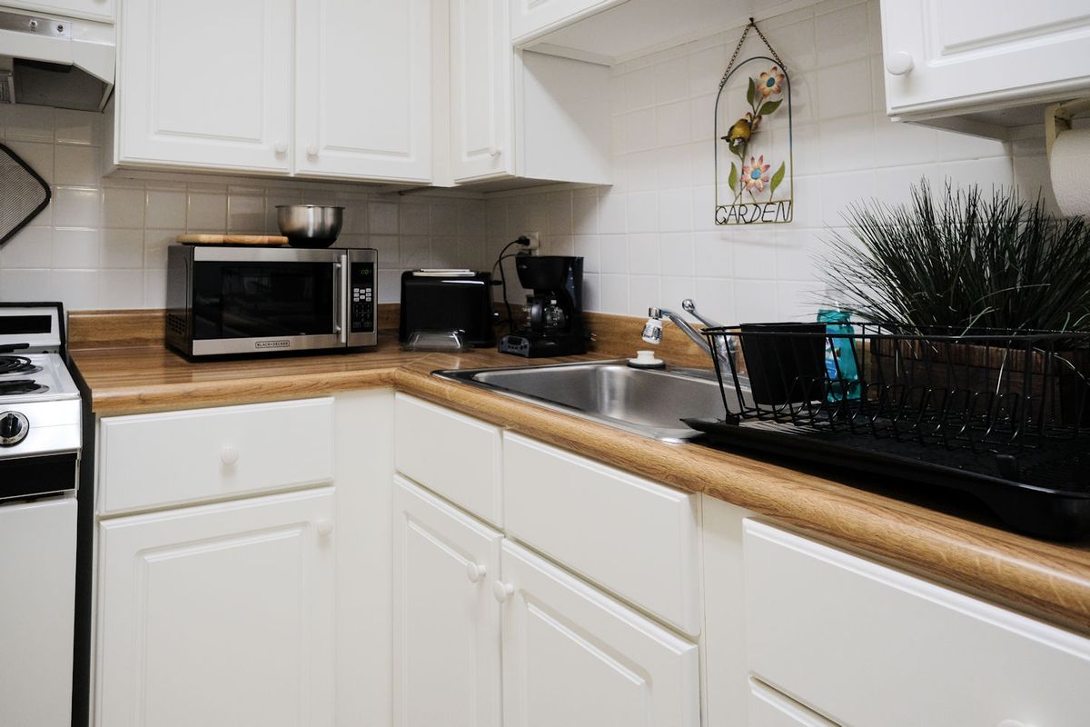 A tidy kitchen corner with white cabinets, a sink, and countertop appliances.