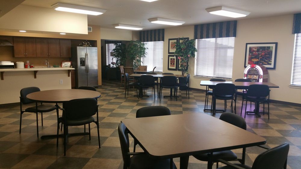 An empty cafeteria with tables, chairs, and large windows.