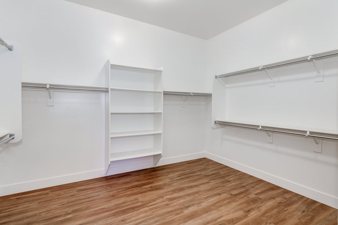 A minimalist interior with white shelving and a hardwood floor.